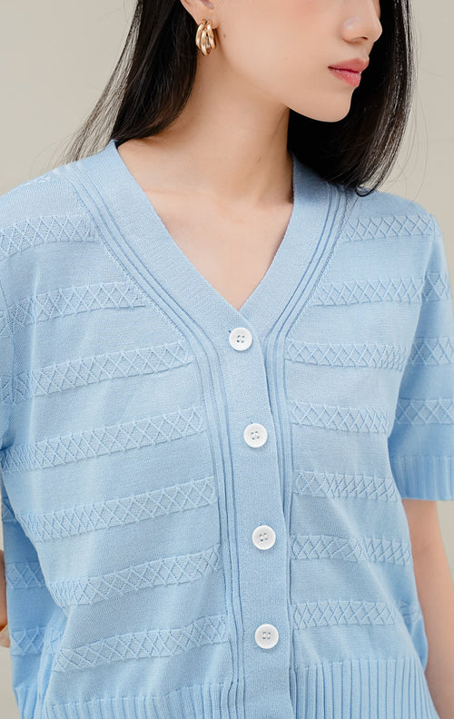 Atasan rajut wanita warna biru muda Maysie Top dengan motif rajut geometris lattice, kerah V-neck, lengan pendek, dan kancing depan elegan. 