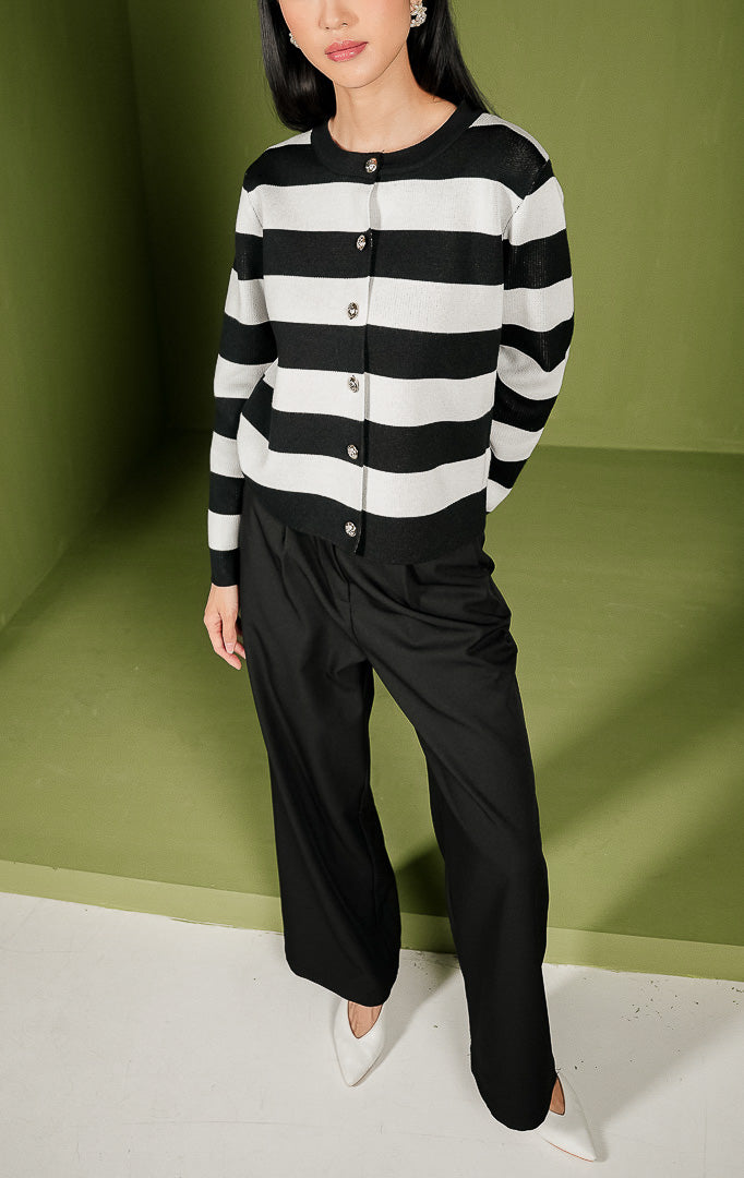 Atasan rajut wanita Mia Top lengan panjang dengan motif garis horizontal berwarna hitam dan putih, dilengkapi kerah bulat (crew neck) dan deretan kancing berwarna emas di bagian depan. 