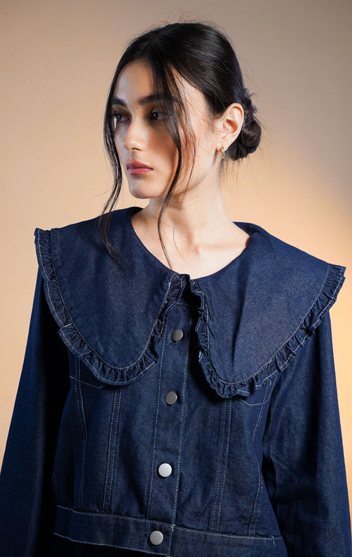 Model wanita mengenakan Mokpo Peter Pan Ruffle Collar Denim Top, atasan denim biru tua (dark wash) dengan kerah lebar model Peter Pan berenda (ruffle trim), kancing depan perak, dan jahitan kontras
