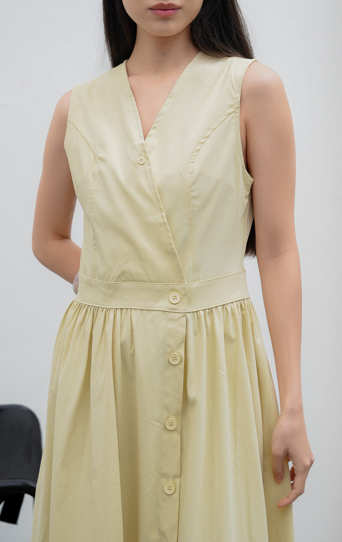 Gaun terusan wanita tanpa lengan (sleeveless dress) warna kuning lembut (butter yellow) Monrow Dress berpotongan A-line berbahan campuran katun-poliester dengan kerah V, detail panelled bodice, dan bukaan kancing depan.