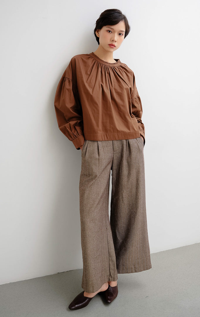 Atasan blouse wanita warna cokelat tua (dark brown) Morgana Top berbahan katun breathable dengan aksen kancing unik pada bagian bahu untuk gaya clean dan minimalist.