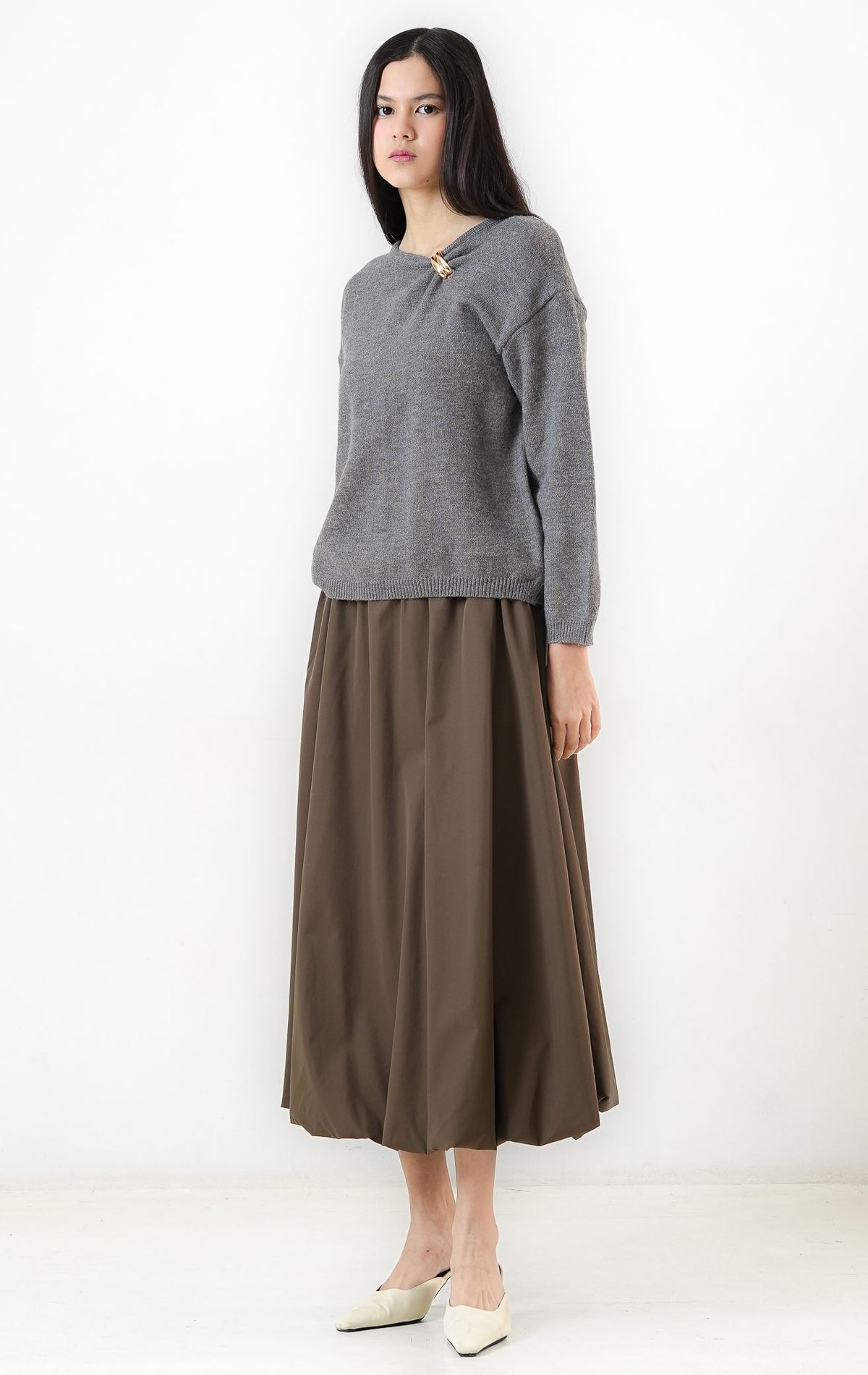 Sweter wanita lengan panjang warna abu-abu (grey) Morvia Sweater berbahan rajut halus (fine-gauge knit) dengan kerah bulat (round neckline), aksen cincin emas di bahu (gold-tone ring detail), dan ujung rajut elastis (ribbed trims). 

