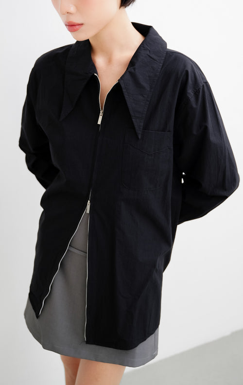Atasan kemeja wanita warna hitam Myra Top berbahan katun ringan dengan kerah oversized sailor, bukaan resleting depan (front zipper), dan kantong dada