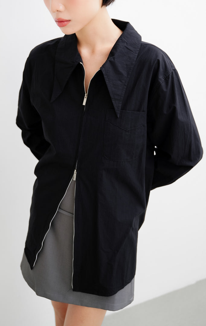 Atasan kemeja wanita warna hitam Myra Top berbahan katun ringan dengan kerah oversized sailor, bukaan resleting depan (front zipper), dan kantong dada
