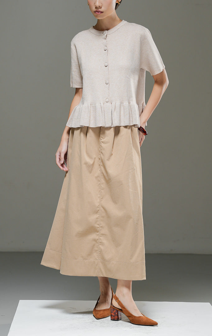 Atasan rajut wanita Naari Top Khaki lengan pendek dengan kerah bulat, kancing depan bungkus, dan detail rumbai (ruffle hem) rajut di bagian bawah. 