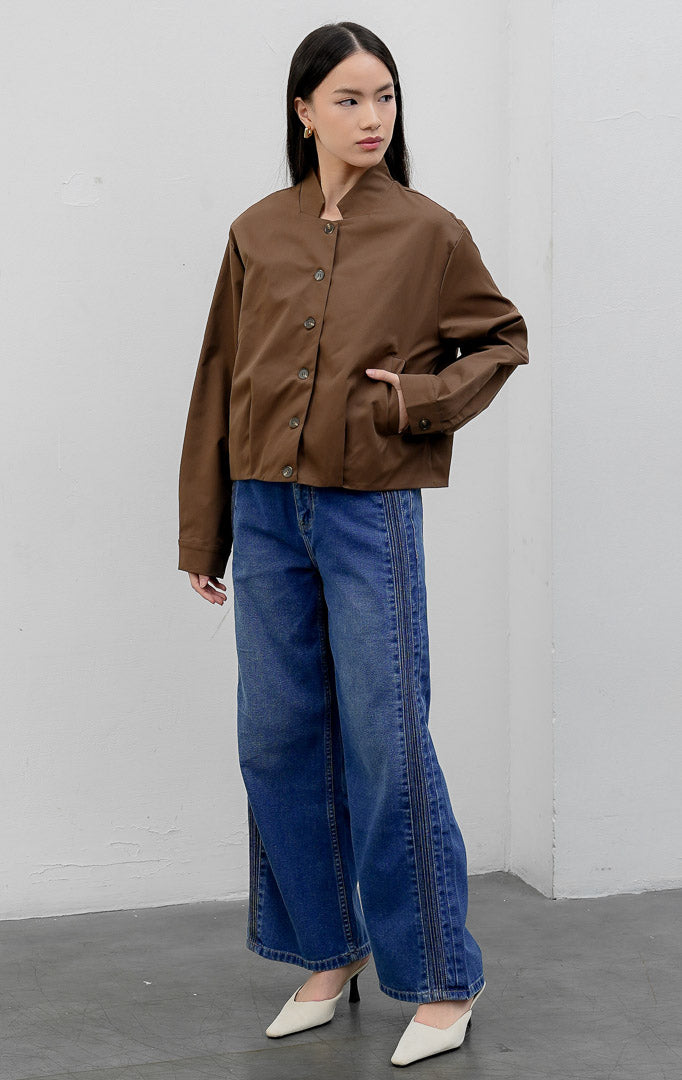 Jaket wanita model bomber tanpa kerah (collarless) warna cokelat tua (dark brown) Nicolette Jacket berbahan campuran katun-nilon dengan kancing depan dan saku samping fungsional.