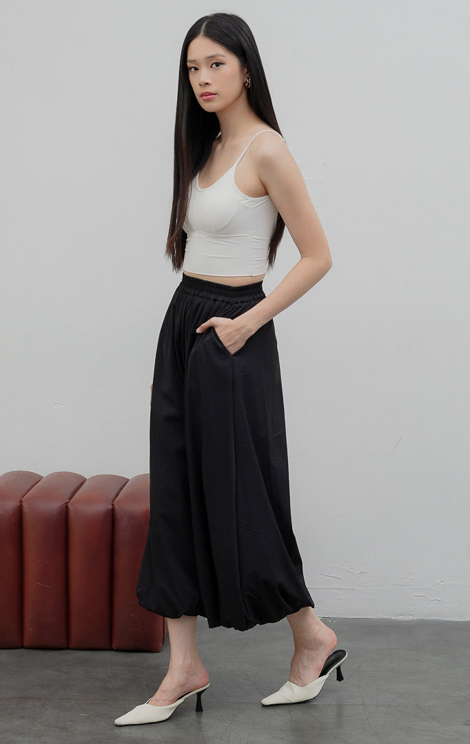Celana panjang wanita model baloon (balloon-leg pants) warna hitam (black) Nikolai Pants berbahan campuran katun nilon dengan detail kerut ujung celana (gathered hem) dan pinggang karet.