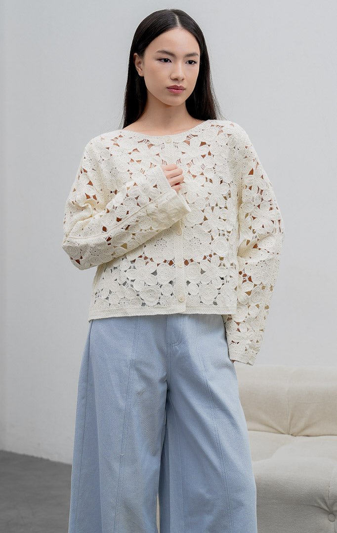 Kardigan rajut wanita lengan panjang warna ivory Novastra Cardigan bermotif renda bunga (floral crochet) dengan bukaan kancing depan dan tekstur open-work.