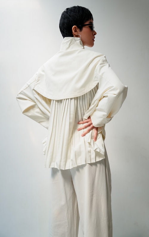 Jaket wanita lengan panjang warna ivory Octoviana Jacket dengan kerah tinggi (high neck), bukaan ritsleting dan kancing cetet (snap-button & zipper closure), saku kantong depan, serta detail lipit di bagian belakang (pleated back).
