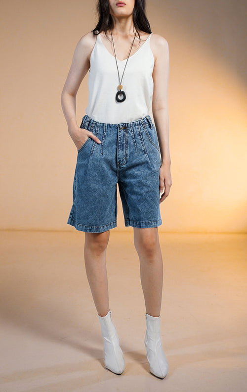 Model wanita mengenakan SH Ophira Short Denim Pants celana pendek denim selutut (Bermuda) dengan pinggang karet dan saku samping, dan dipadukan dengan tank top hitam
