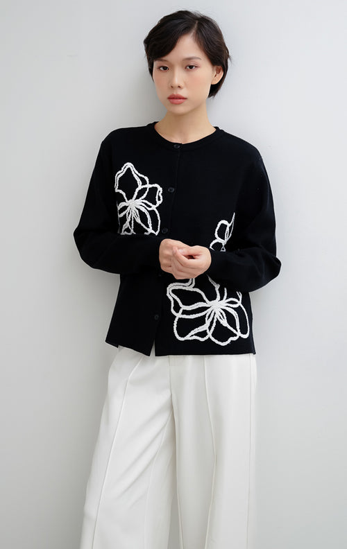 Cardigan rajut wanita warna hitam Peppie Cardigan berbahan soft stretch dengan detail bordir bunga (flower embroidery) dan kancing depan (button-up).