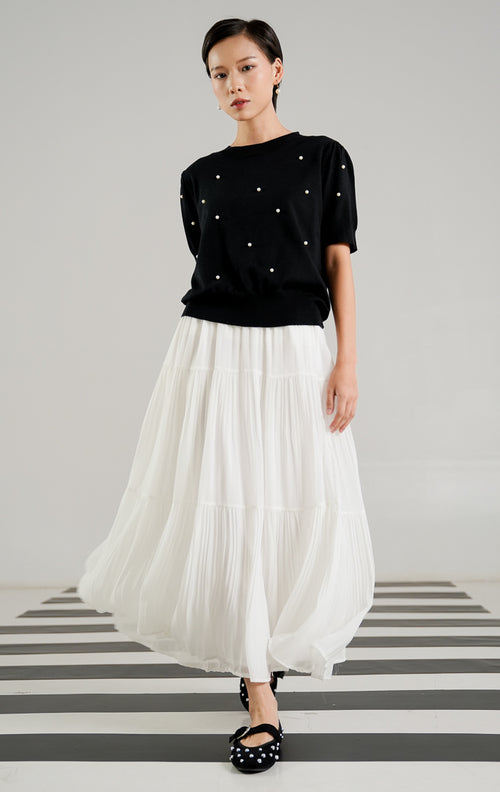 Atasan rajut lengan pendek wanita Polina Top Black dengan detail hiasan mutiara putih (pearls) yang tersebar di bagian depan, kerah bulat (crew neck), dan rib pada ujung lengan. 