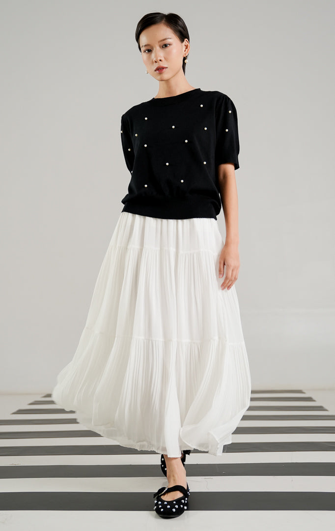 Atasan rajut lengan pendek wanita Polina Top Black dengan detail hiasan mutiara putih (pearls) yang tersebar di bagian depan, kerah bulat (crew neck), dan rib pada ujung lengan. 
