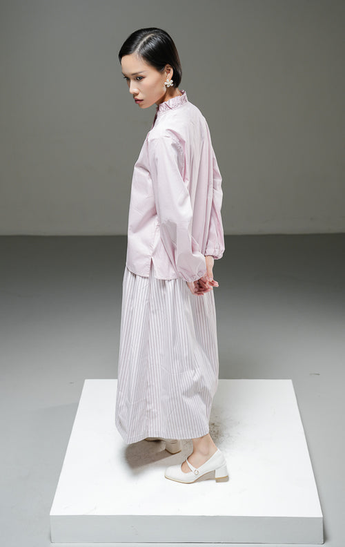 Baju atasan wanita lengan panjang Raffaella Top warna dusty pink polos dengan detail kerah ruffle, aksen rumbai lipit di bagian bukaan kancing depan, dan ujung lengan berkaret. 