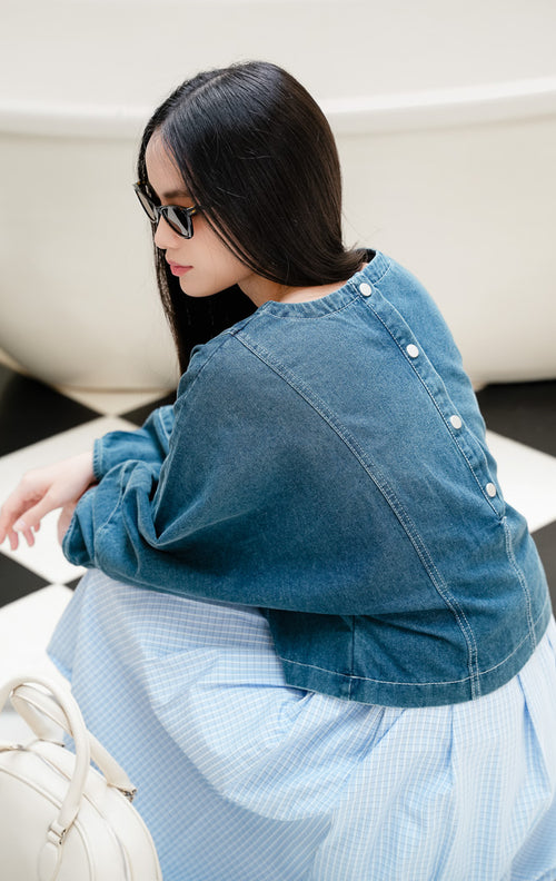 Atasan blouse denim jeans wanita Rainhold Top warna biru denim dengan detail kancing di bagian belakang dan siluet kasual yang modern. 