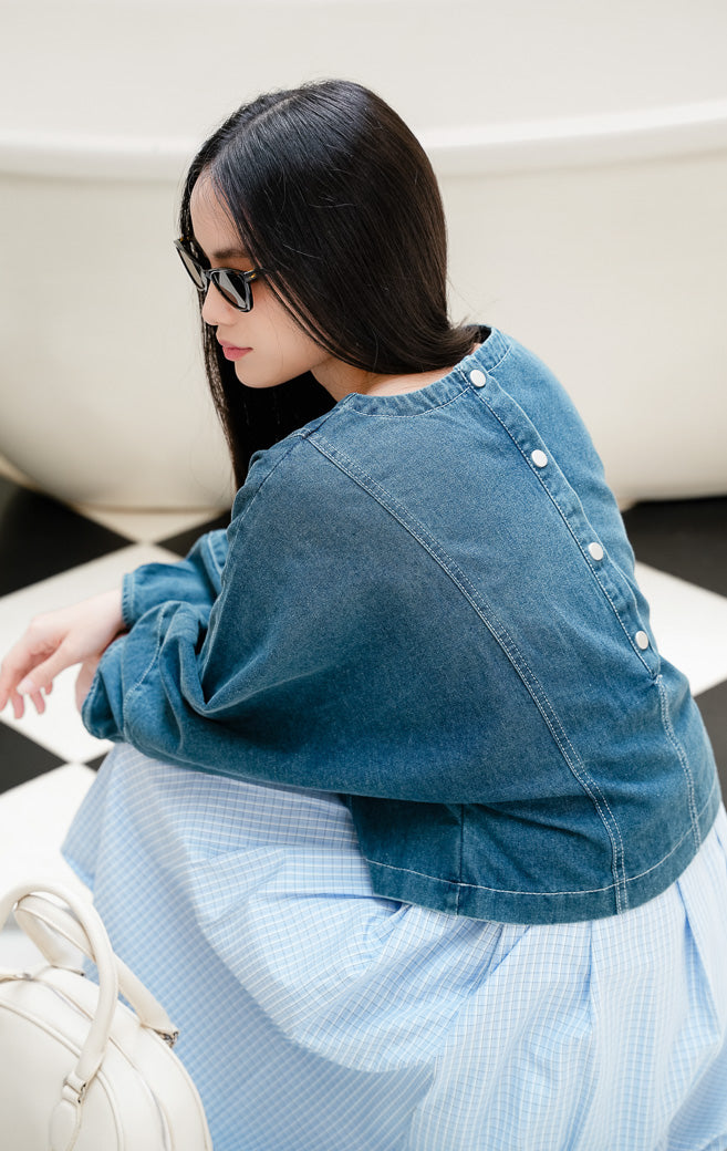 Atasan blouse denim jeans wanita Rainhold Top warna biru denim dengan detail kancing di bagian belakang dan siluet kasual yang modern. 