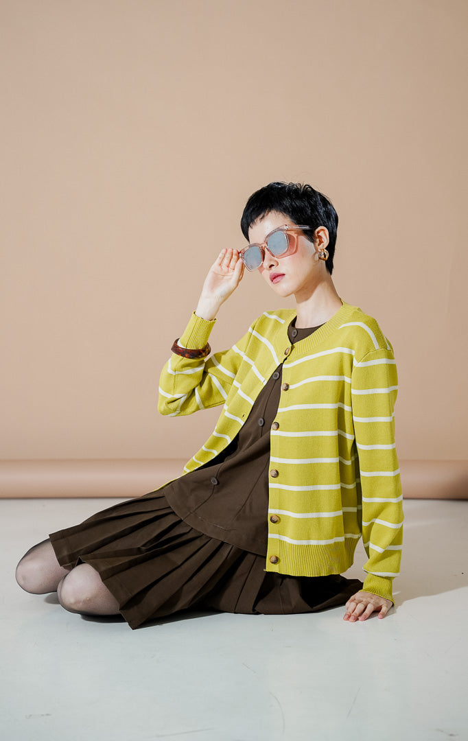 Model wanita mengenakan Freja Cardigan Lime, kardigan rajut berwarna hijau lime dengan motif garis-garis (stripe) putih dan kancing depan yang stylish dari This Is April.