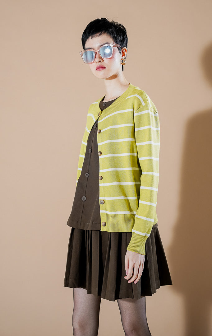 Model wanita mengenakan Freja Cardigan Lime, kardigan rajut berwarna hijau lime dengan motif garis-garis (stripe) putih dan kancing depan yang stylish dari This Is April.