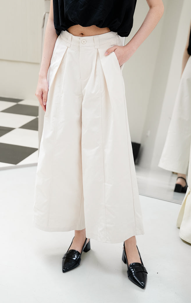 Celana panjang wanita Renata Wide-Leg Pants warna ivory (gading) berpotongan wide-leg dengan detail lipit depan (front pleats), kancing depan, dan pinggang karet belakang untuk tampilan smart-casual. 
