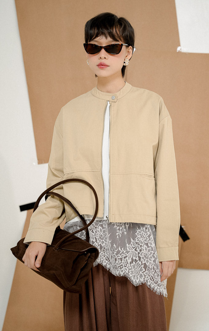Model mengenakan Renley Crop Bomber Jacket Khaki, produk jaket bomber wanita potongan crop lengan panjang warna khaki krem dengan kerah shanghai dan resleting depan. 