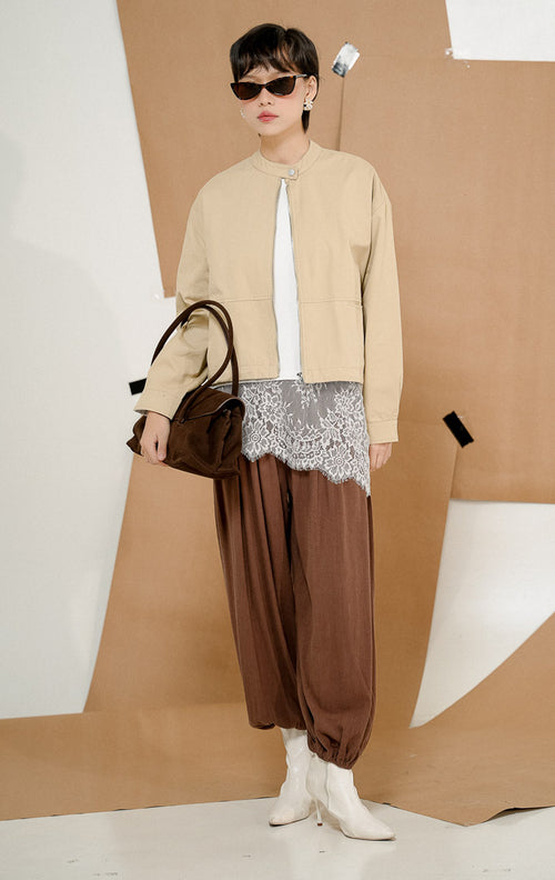 Model mengenakan Renley Crop Bomber Jacket Khaki, produk jaket bomber wanita potongan crop lengan panjang warna khaki krem dengan kerah shanghai dan resleting depan. 