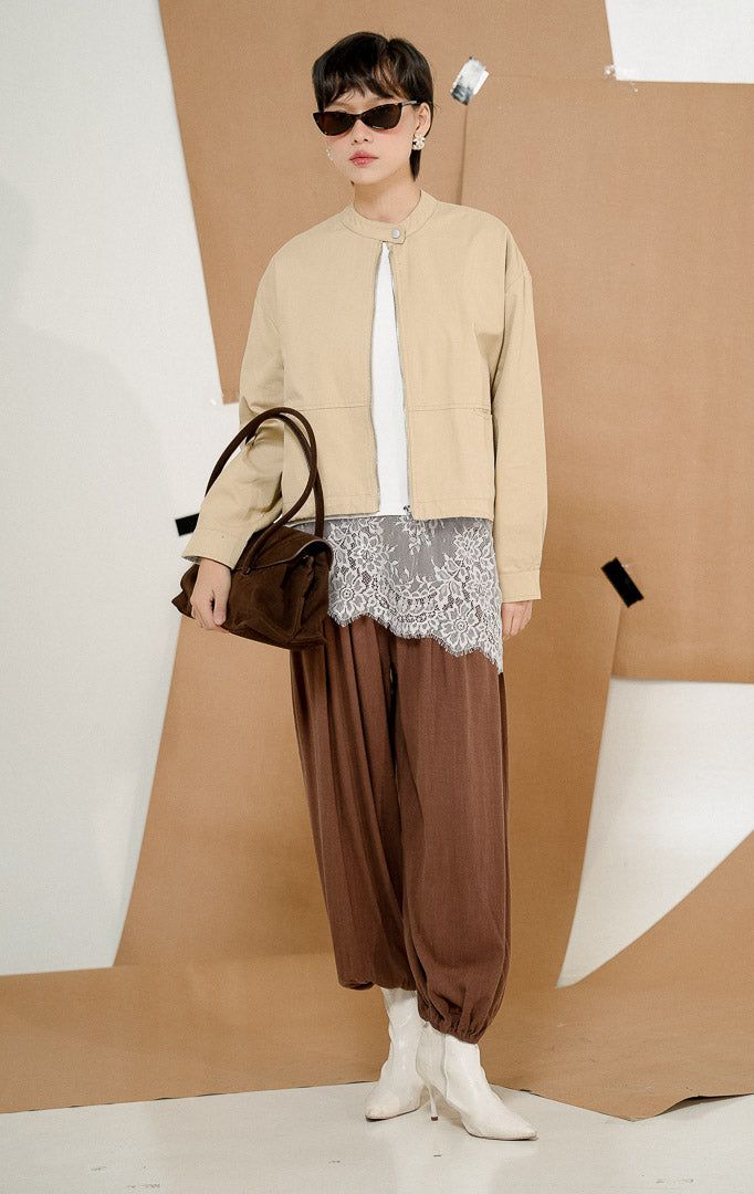 Model mengenakan Renley Crop Bomber Jacket Khaki, produk jaket bomber wanita potongan crop lengan panjang warna khaki krem dengan kerah shanghai dan resleting depan. 