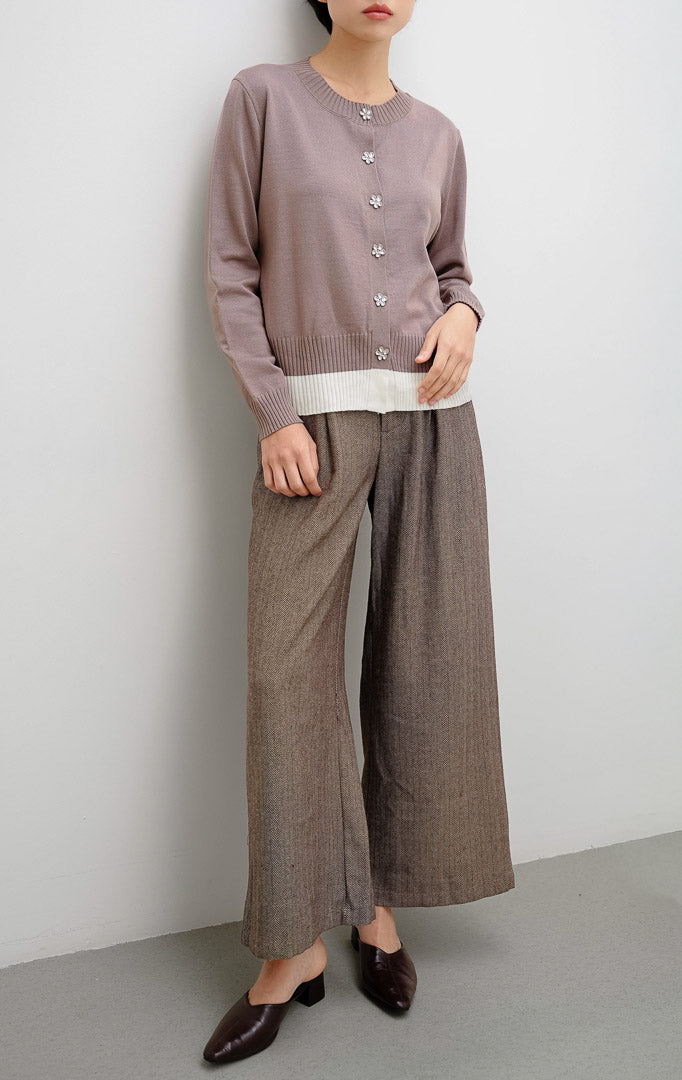 Cardigan rajut wanita warna cokelat (brown) Revie Cardigan dengan detail kancing bentuk bunga (floral button), aksen pinggiran warna ivory, dan siluet relaxed fit.