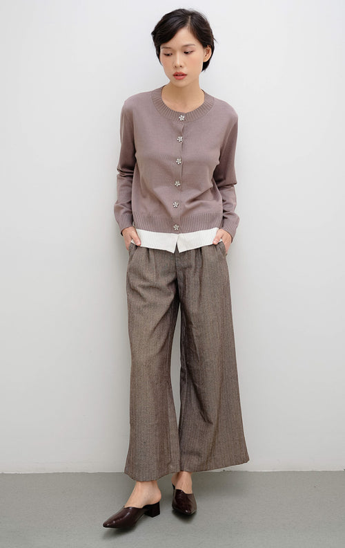 Cardigan rajut wanita warna cokelat (brown) Revie Cardigan dengan detail kancing bentuk bunga (floral button), aksen pinggiran warna ivory, dan siluet relaxed fit.