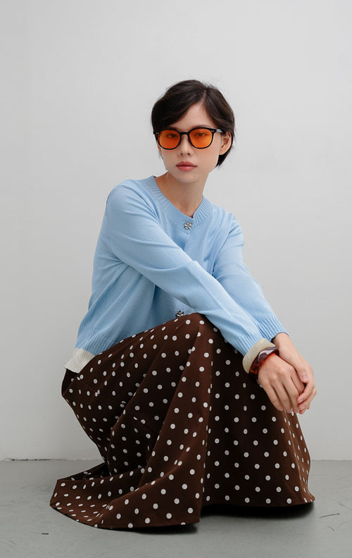 Cardigan rajut wanita warna biru muda (light blue) Revie Cardigan dengan detail kancing bentuk bunga (floral button), aksen pinggiran warna ivory, dan siluet relaxed fit.