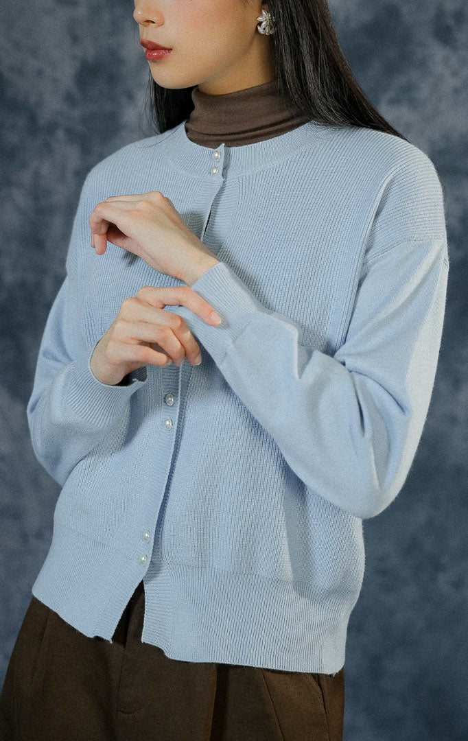 Cardigan lengan panjang wanita Rivere warna biru muda (light blue) berbahan rajut premium dengan detail dua kancing depan bergaya mutiara. 

