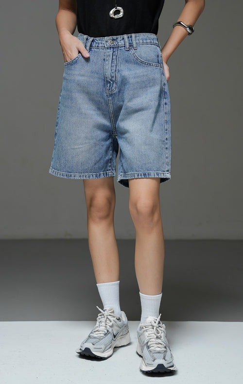 Celana pendek jeans wanita Rivora Pants warna denim biru muda washed dengan potongan relaxed fit, kancing depan, zip fly, dan saku fungsional. 