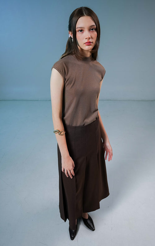 Model wanita mengenakan Shannon Pleated Maxi Skirt warna dark brown, rok panjang wanita model high waist berwarna coklat tua dengan detail lipit depan yang elegan. 