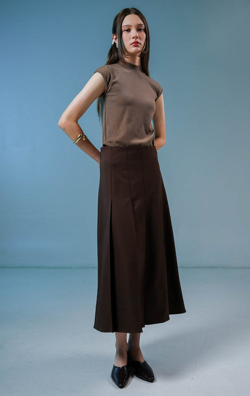 Model wanita mengenakan Shannon Pleated Maxi Skirt warna dark brown, rok panjang wanita model high waist berwarna coklat tua dengan detail lipit depan yang elegan. 