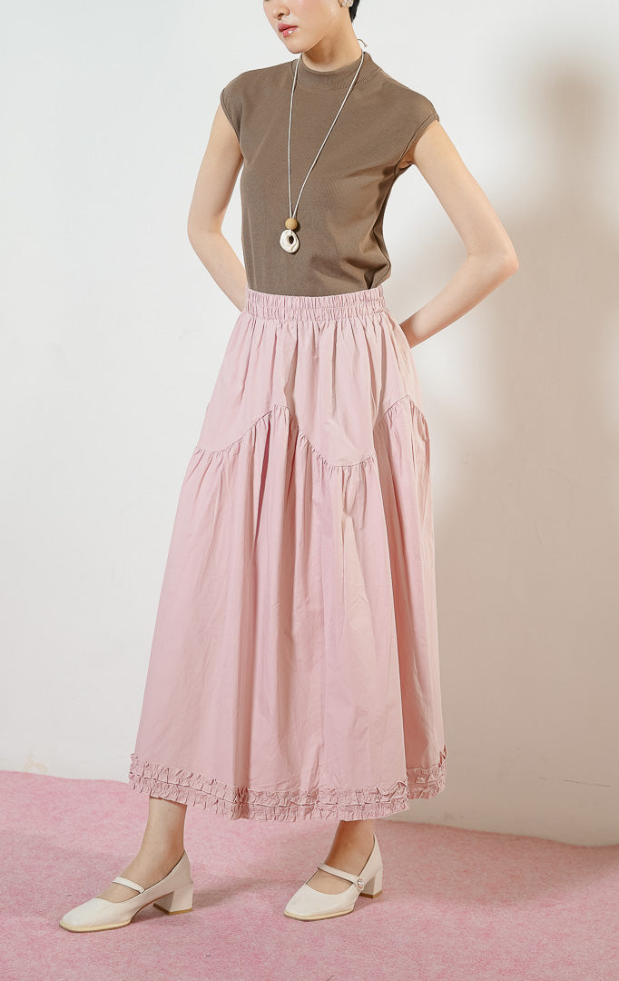 Model wanita mengenakan Lacey Tiered Ruffle Hem Skirt warna dusty pink, rok panjang katun wanita berwarna merah muda dengan pinggang karet dan detail kelim kerut rumbai yang feminin. 