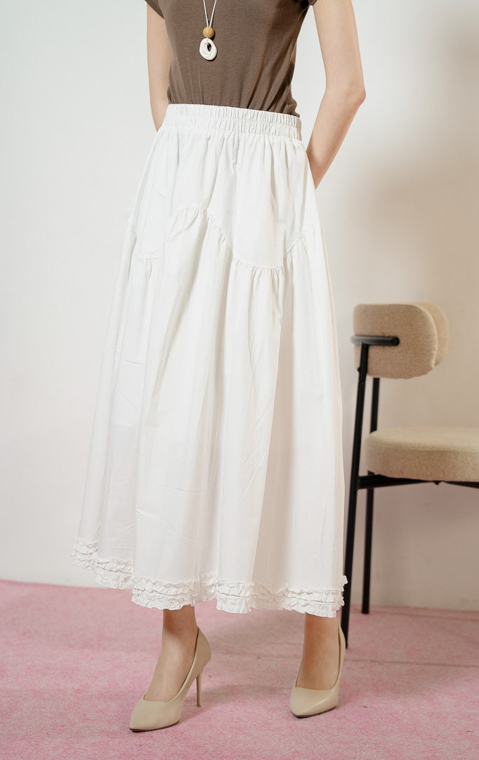 Model wanita mengenakan Lacey Tiered Ruffle Hem Skirt warna white, rok panjang katun wanita berwarna putih dengan pinggang karet dan detail kelim kerut rumbai yang feminin. 