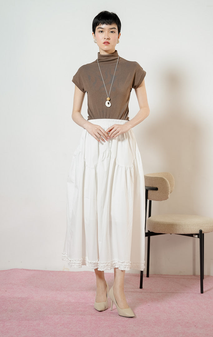 Model wanita mengenakan Lacey Tiered Ruffle Hem Skirt warna white, rok panjang katun wanita berwarna putih dengan pinggang karet dan detail kelim kerut rumbai yang feminin. 