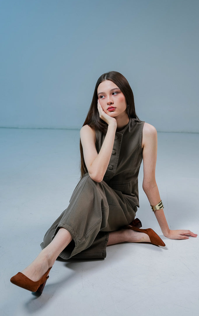 Model wanita mengenakan Rielle Two-Pocket Button-Up Vest warna brown, atasan rompi vest denim wanita berwarna coklat dengan kancing depan dan detail kantong samping. 