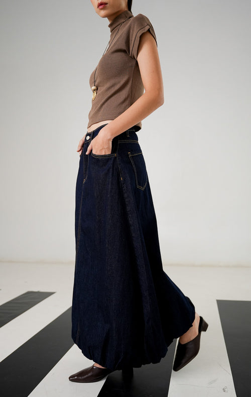 Rok denim panjang wanita Rouje Skirt Dark Blue dengan siluet balloon, detail jahitan vertikal di tengah, dan karet pinggang belakang yang nyaman. 