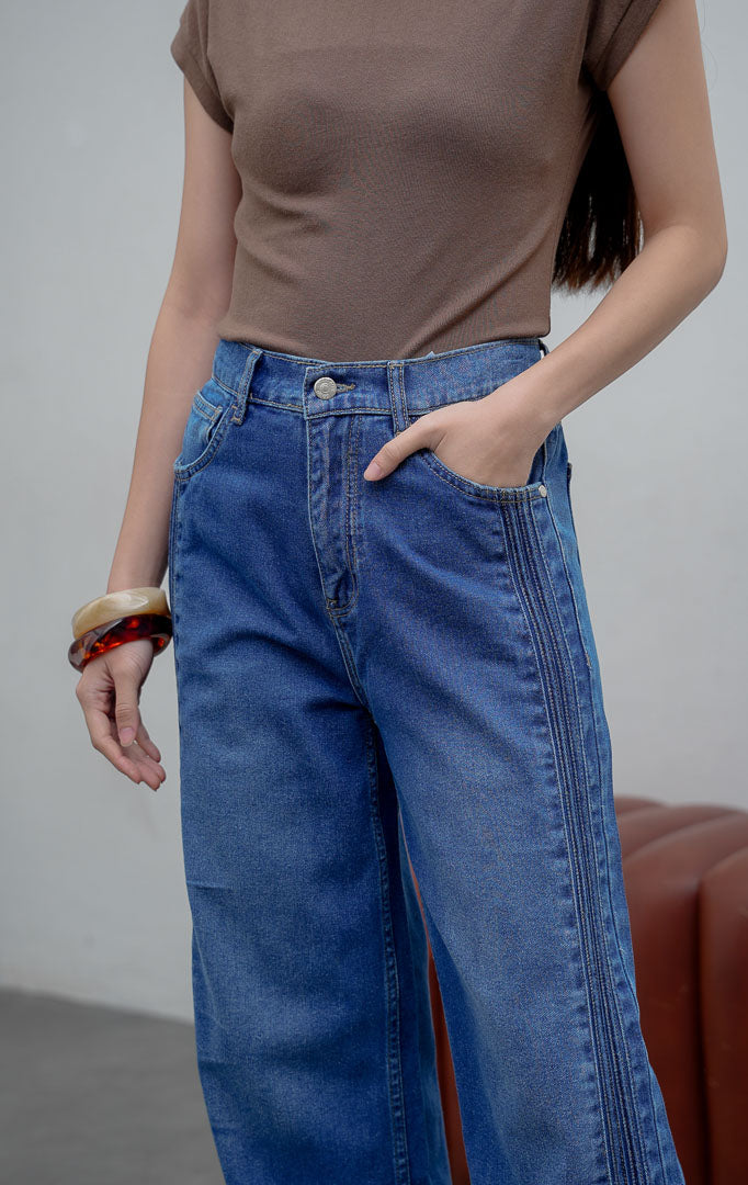 Celana jeans wanita model lurus (straight leg) warna biru medium (denim) Rovex Pants dengan aksen jahitan lipit samping (pintuck detailing), saku fungsional, dan pinggang karet belakang. 