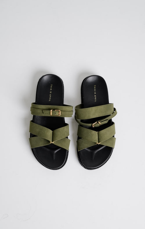 Tampilan flat lay sepasang Violet Sandals warna olive, sandal flat teplek wanita tali menyilang bahan suede hijau zaitun dengan gesper emas dan sol tebal gerigi hitam dari This Is April.