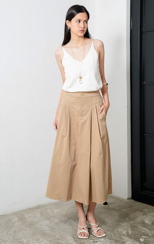 Rok midi model A-line santai warna khaki (khaki relaxed A-line skirt) Scarlette Skirt dengan ban pinggang terstruktur (structured waistband), bukaan kancing depan (front button closure), dan detail lipit halus di bagian pinggang (subtle pleat detailing). 

