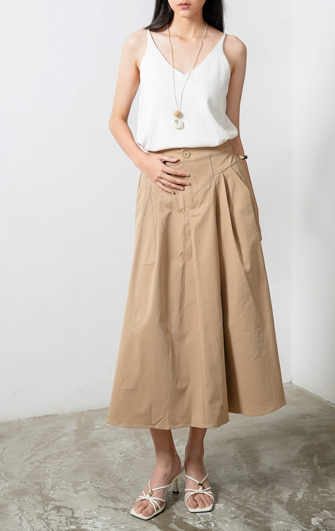 Rok midi model A-line santai warna khaki (khaki relaxed A-line skirt) Scarlette Skirt dengan ban pinggang terstruktur (structured waistband), bukaan kancing depan (front button closure), dan detail lipit halus di bagian pinggang (subtle pleat detailing). 

