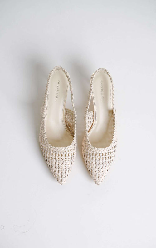 Tampilan flat lay sepasang Avaia Heels warna ivory, sepatu hak rendah wanita model slingback heels ujung runcing pointed toe bahan kulit anyaman warna putih gading dari This Is April. 