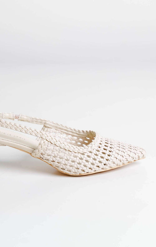 Tampilan flat lay sepasang Avaia Heels warna ivory, sepatu hak rendah wanita model slingback heels ujung runcing pointed toe bahan kulit anyaman warna putih gading dari This Is April. 