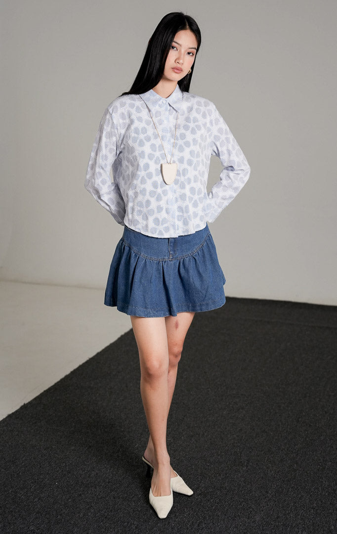 Serena Top Blue, kemeja katun lengan panjang dengan motif garis-garis biru putih dan aksen pola bunga, dipadukan dengan rok mini jeans denim