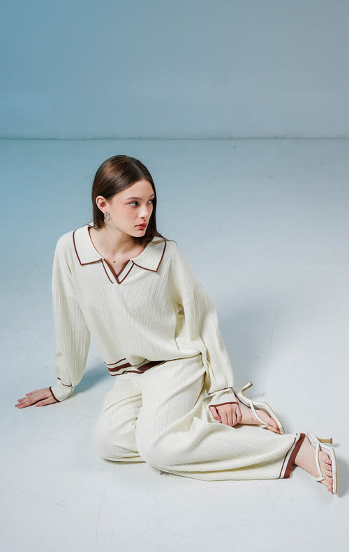 Model wanita mengenakan Margarite Contrast Trim Ribbed Collared Knit Set warna ivory, setelan one set rajut wanita lengan panjang bertekstur rib dengan detail garis kontras cokelat. 