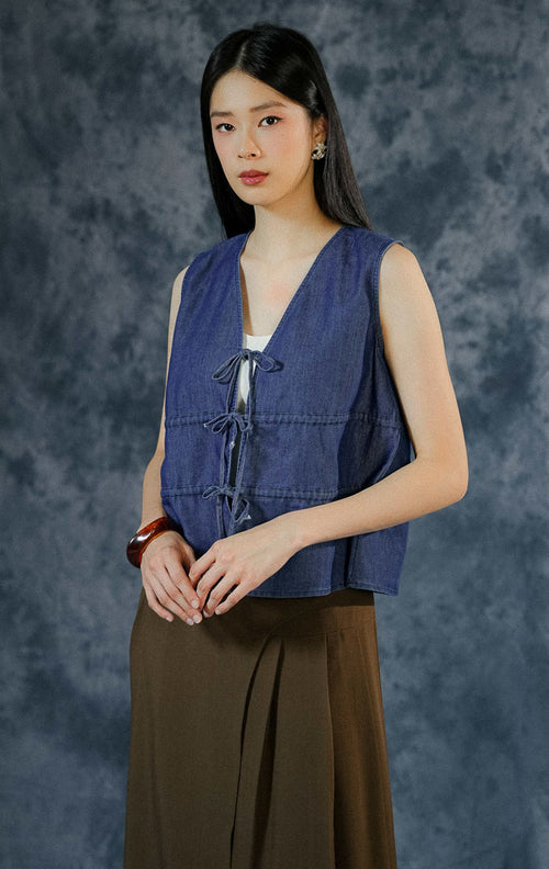 Atasan tanpa lengan (sleeveless) wanita Shirleigh berbahan denim dengan potongan leher v-cut dan detail tali serut aktif (ruched) di bagian dada depan. 


