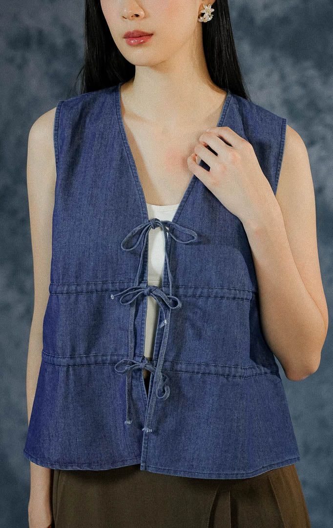Atasan tanpa lengan (sleeveless) wanita Shirleigh berbahan denim dengan potongan leher v-cut dan detail tali serut aktif (ruched) di bagian dada depan. 

