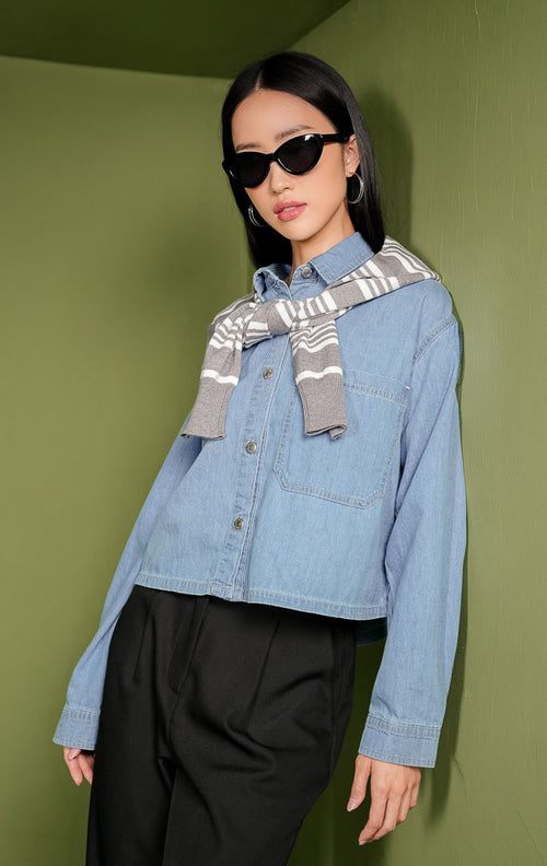 Atasan kemeja wanita Silfira Top berbahan denim warna biru klasik lengan panjang, dilengkapi kerah rapi, deretan kancing metal di bagian depan, serta satu saku fungsional di dada sebelah kiri.
