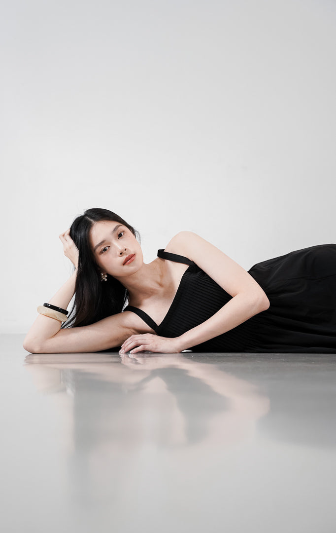 Skylar Dress warna hitam, gaun A-line tanpa lengan dengan detail lipatan pintuck vertikal di bagian dada dan tali bahu yang bisa diatur.

